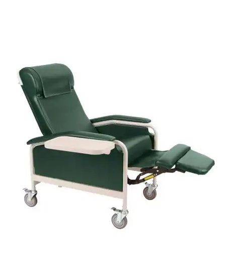 A dark green adjustable medical recliner chair with a white metal frame and casters, featuring an extended footrest and a built-in white tray table.