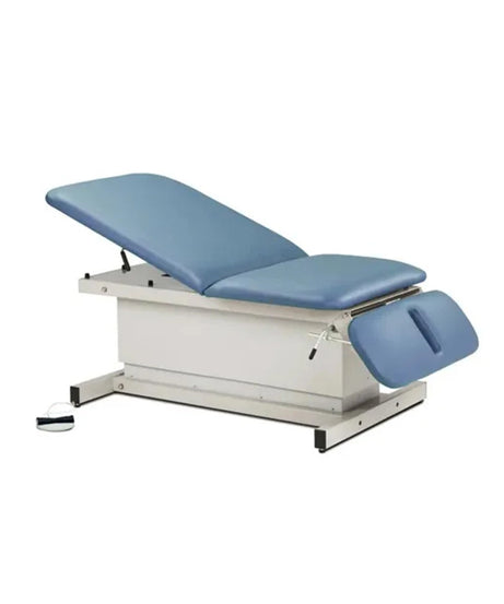 An adjustable medical examination table with blue padded surfaces and a white metal frame, shown on a plain white background.