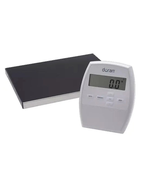 A Doramy digital kitchen scale with a white plastic control unit displaying '0.0 g' and a rectangular black weighing platform with a silver edge, shown on a plain white background.