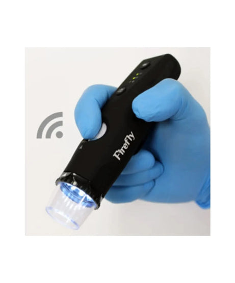 A black handheld Firefly device with a clear tip, held in a hand wearing a blue nitrile glove. The device has a white logo and a small green LED indicator light.