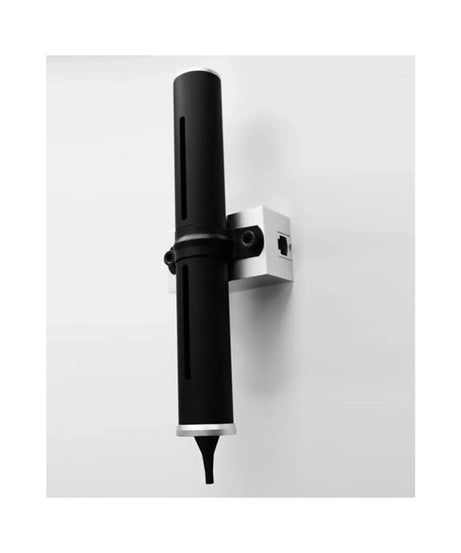 A modern wall-mounted light fixture with a matte black cylindrical shade and a silver metal bracket, shown against a plain light gray wall.