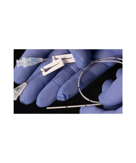 A close-up of gloved hands holding a thin, flexible metallic tube or catheter with attached clear plastic components against a black background.