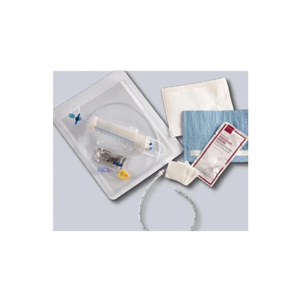 A medical dressing kit containing a clear plastic tray with a syringe, gauze pads, a blue bandage, and a packaged wound dressing, arranged on a light gray background.